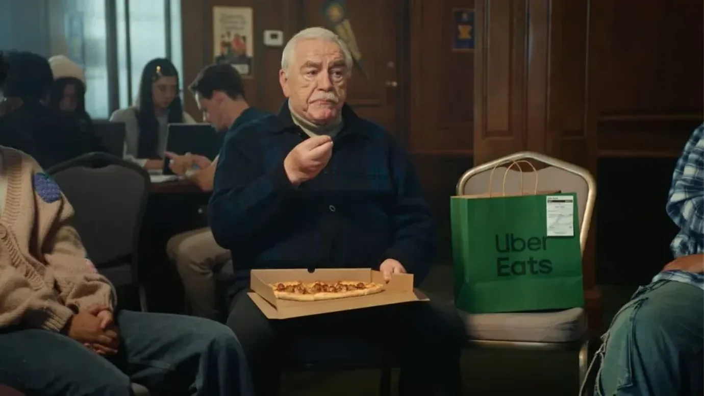 Actor Brian Cox in a commercial, eating a slice of pizza.